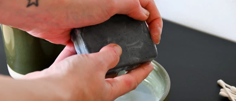 Hands holding charcoal soap