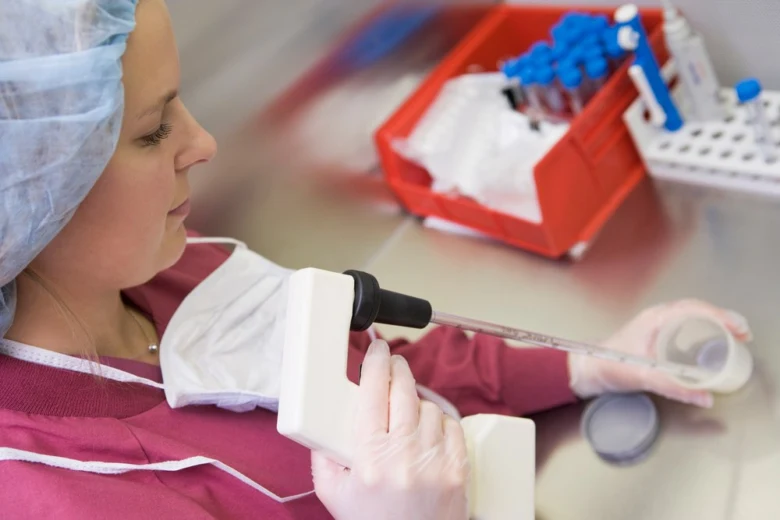 Žena v laboratoři používá pipetu při umělém oplodnění.