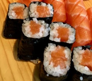 Sushi rolly s lososem a nigiri na dřevěném talíři.
