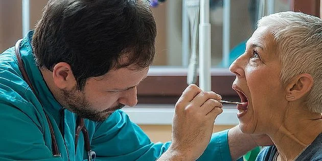 Lékař vyšetřuje hrdlo pacientky pomocí nástroje.
