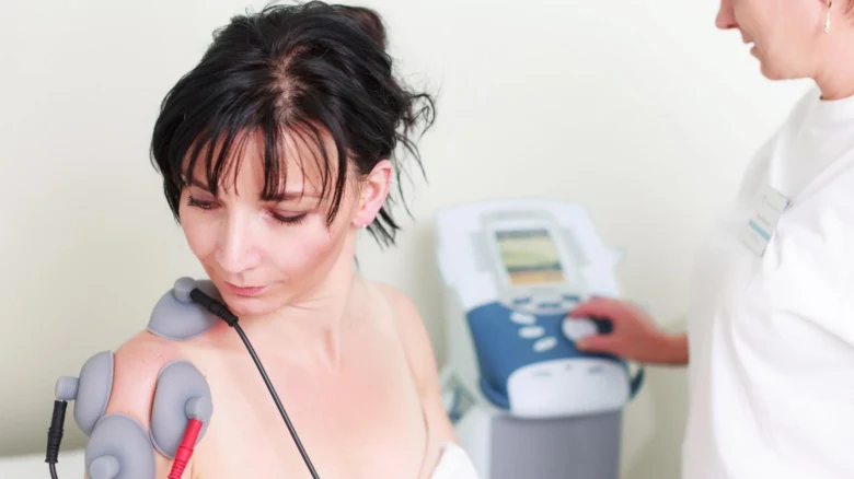 Žena dostává fyzioterapii ramene v lázeňském zařízení.