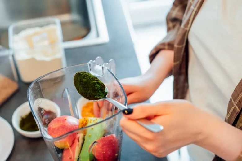 Person adding spirulina to blender