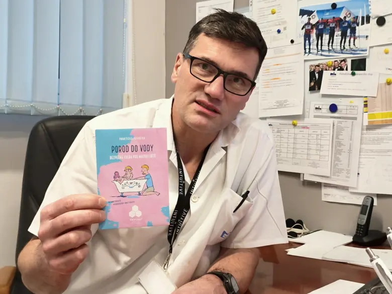 Muž drží brožuru o porod do vody v kanceláři.