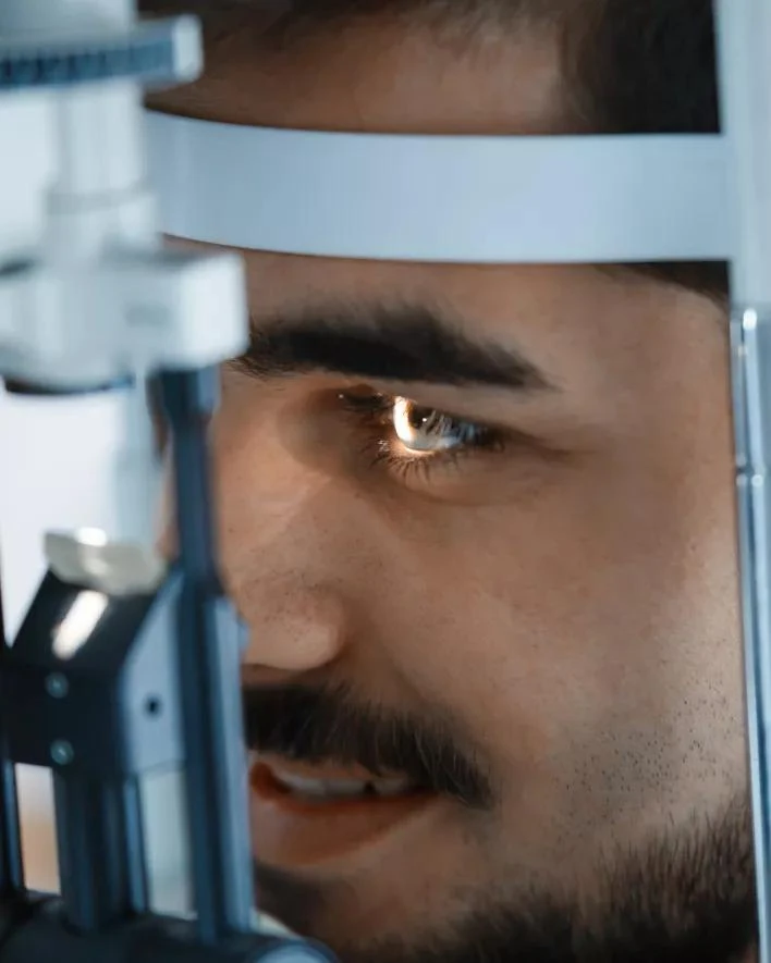 Muž podstupuje vyšetření zraku na optometrickém přístroji.